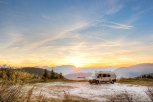 Small Motor Home parked outdoors in the mountains during sunset in autumn.